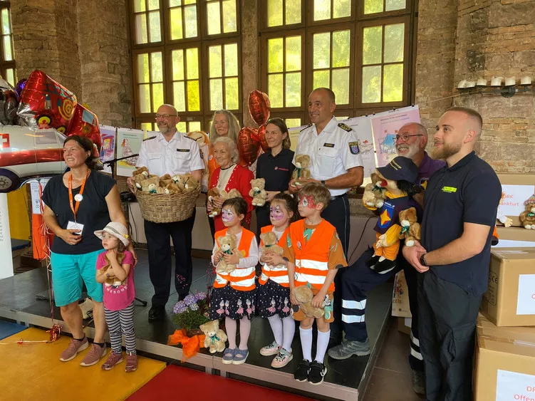 Senatorin Karin Giersch von der Giersch Stiftung (rote Jacke) mit Einsatzkräften, Kindern und Teddybären.